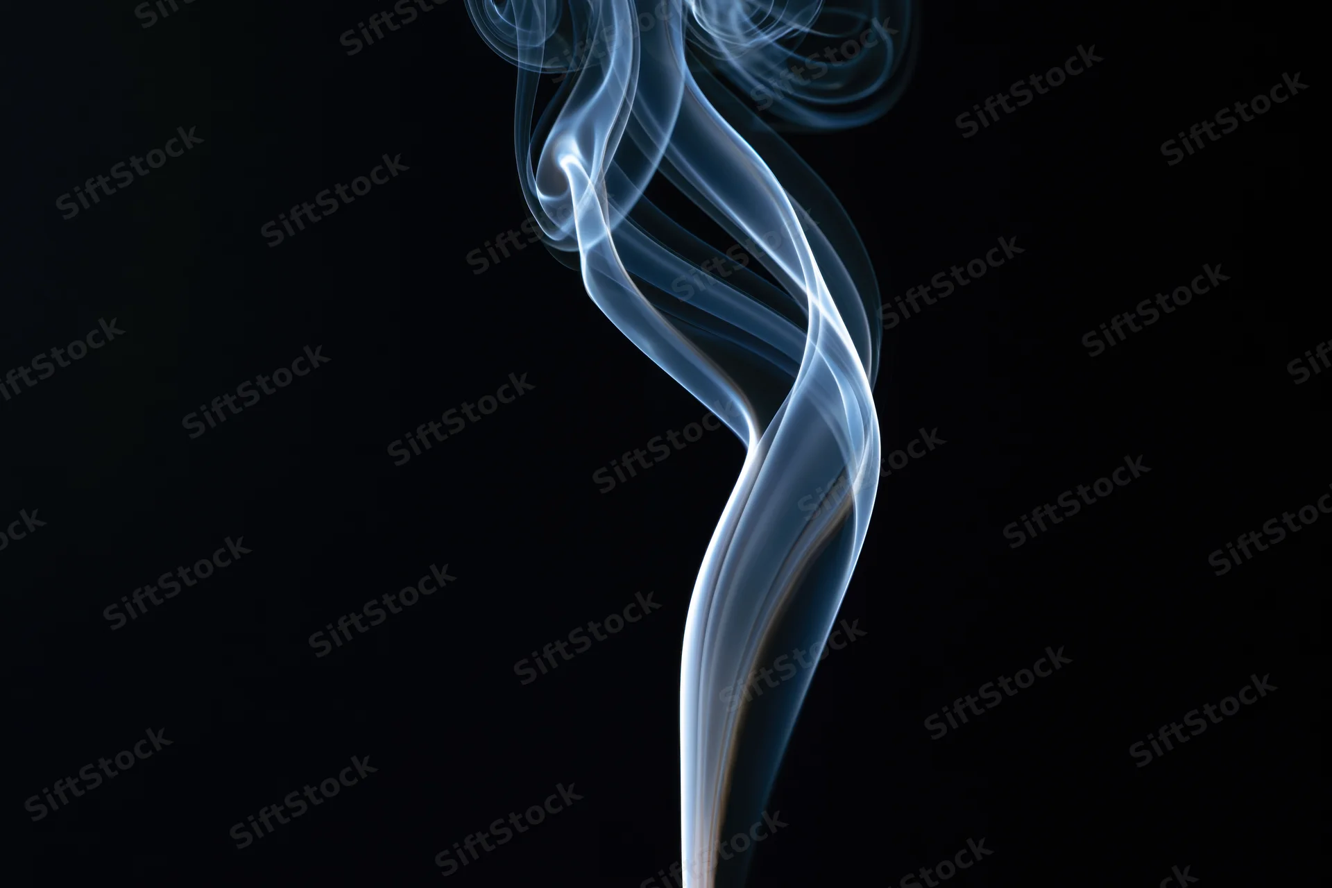 Thin ribbon of incense smoke curling and twisting upward against black background
