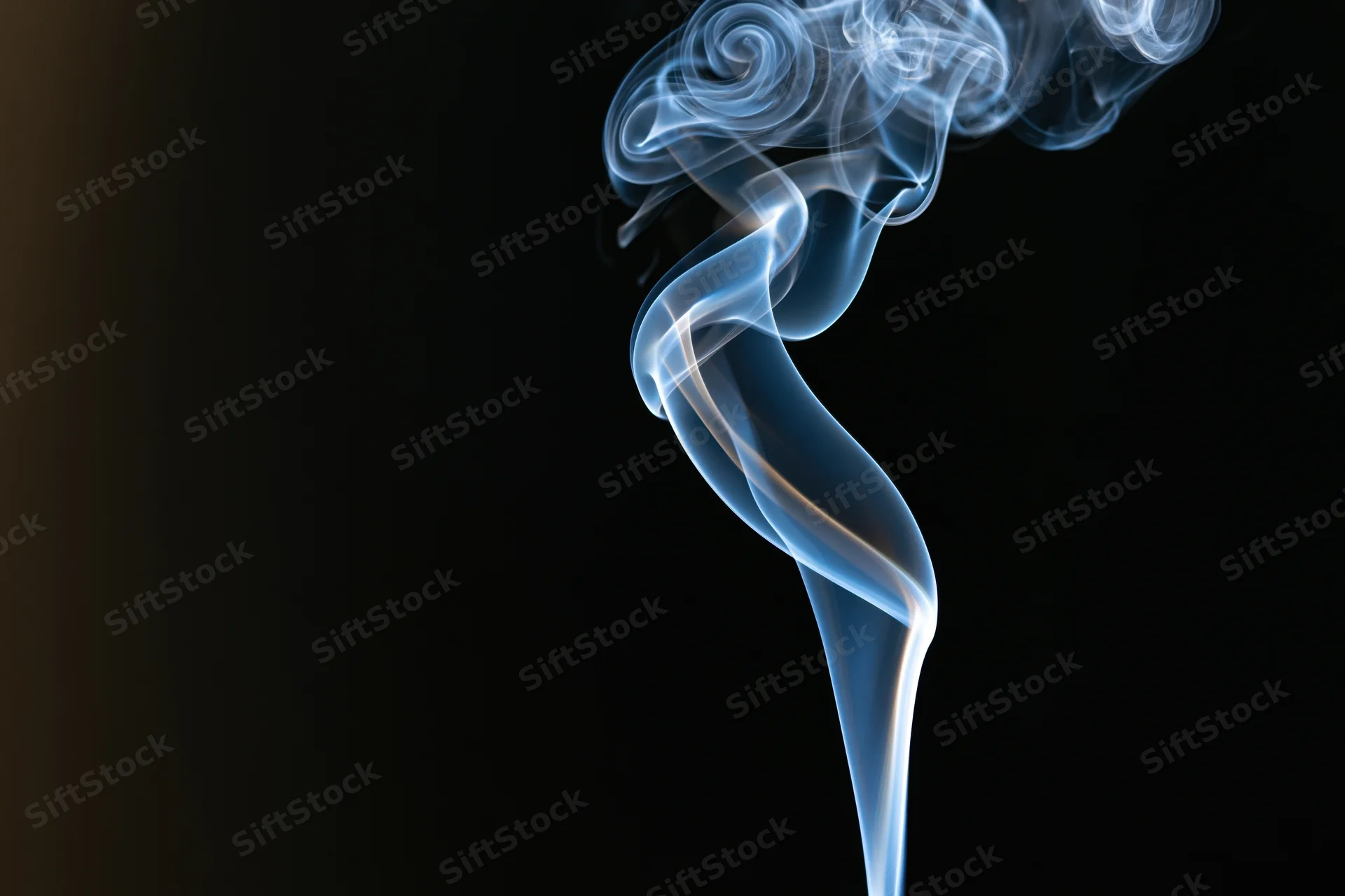 Thin ribbon of incense smoke curling and twisting upward against a dark background