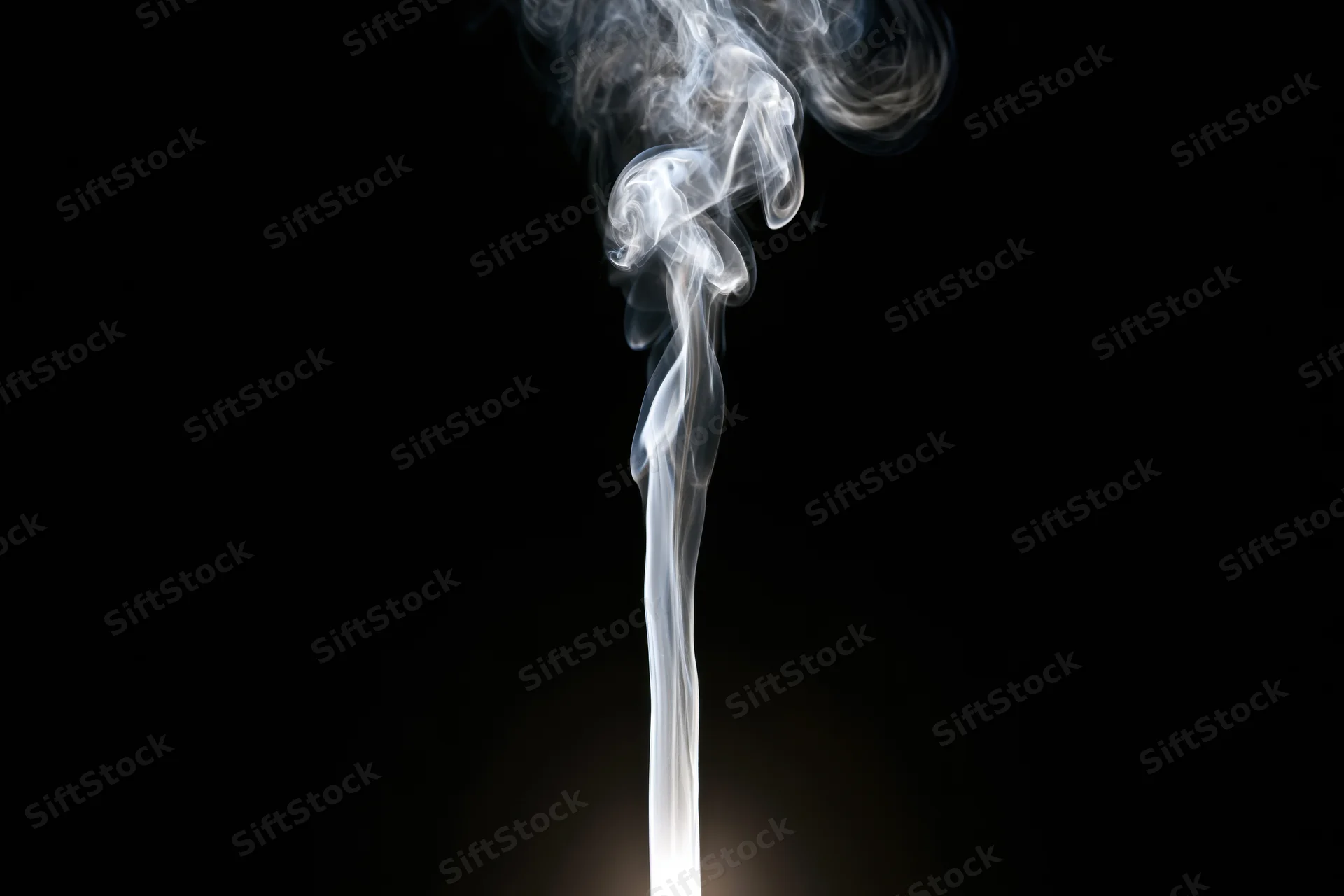 Thin wisp of white smoke rising and curling upward against black background