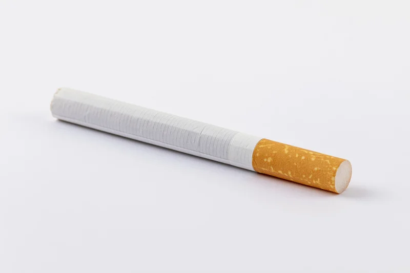Unlit cigarette lying horizontally on white background in closeup macro view