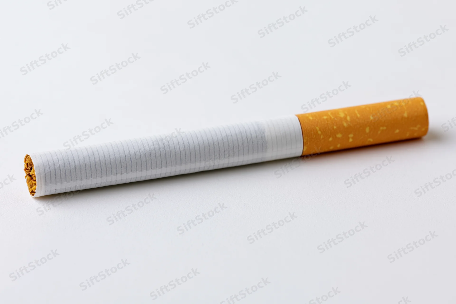 Unlit cigarette lying horizontally on white surface in closeup macro view