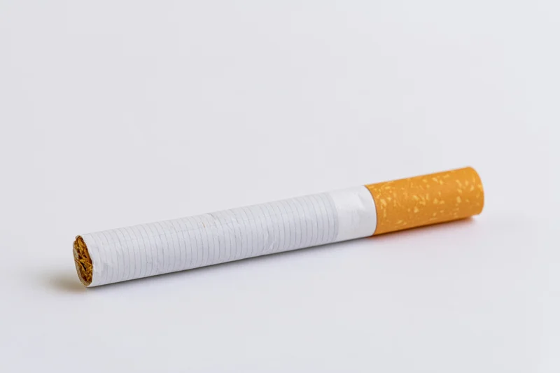 Unlit cigarette lying horizontally on white surface in closeup macro view