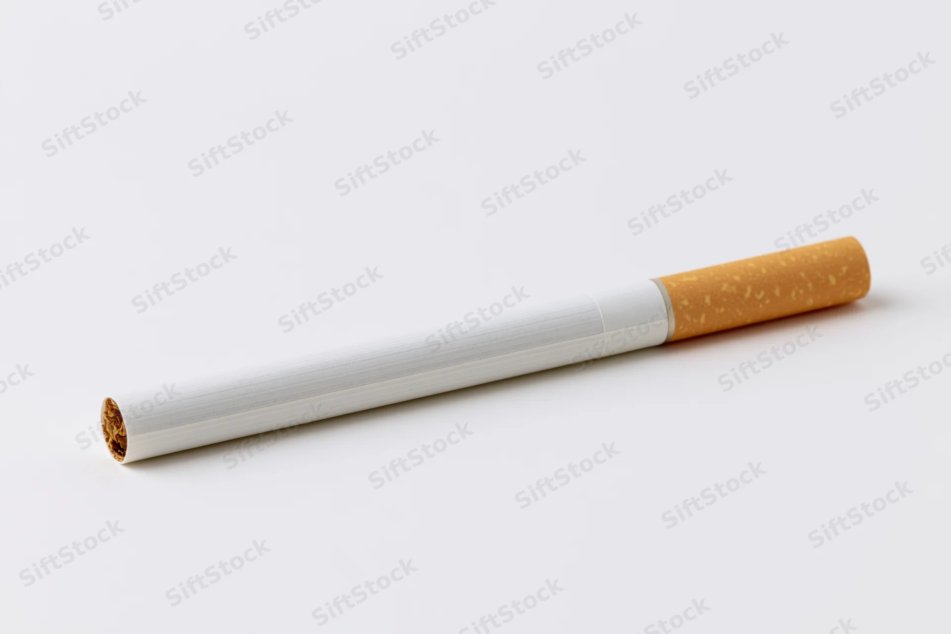 Unlit cigarette lying horizontally on plain white background