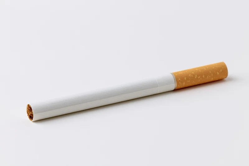 Unlit cigarette lying horizontally on plain white background
