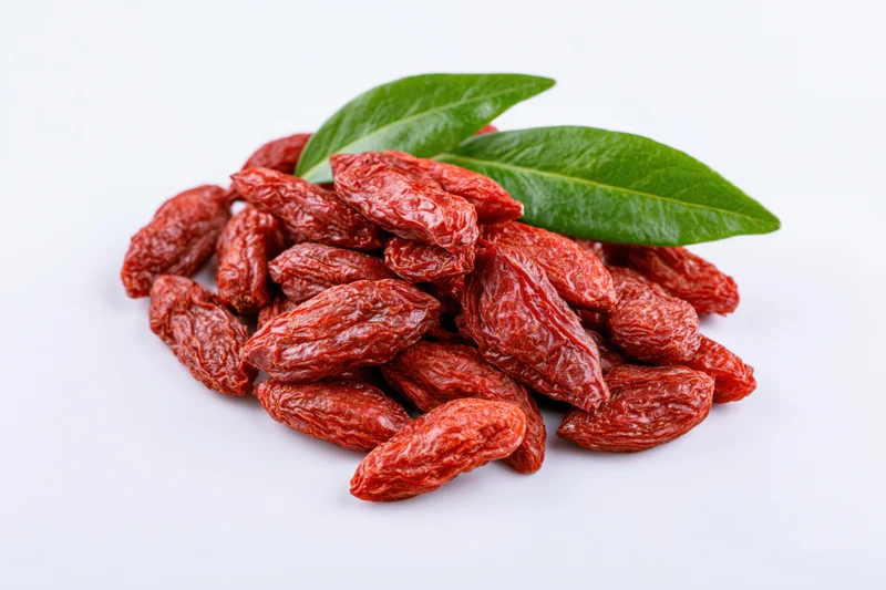 Pile of dried goji berries with two green leaves on white background