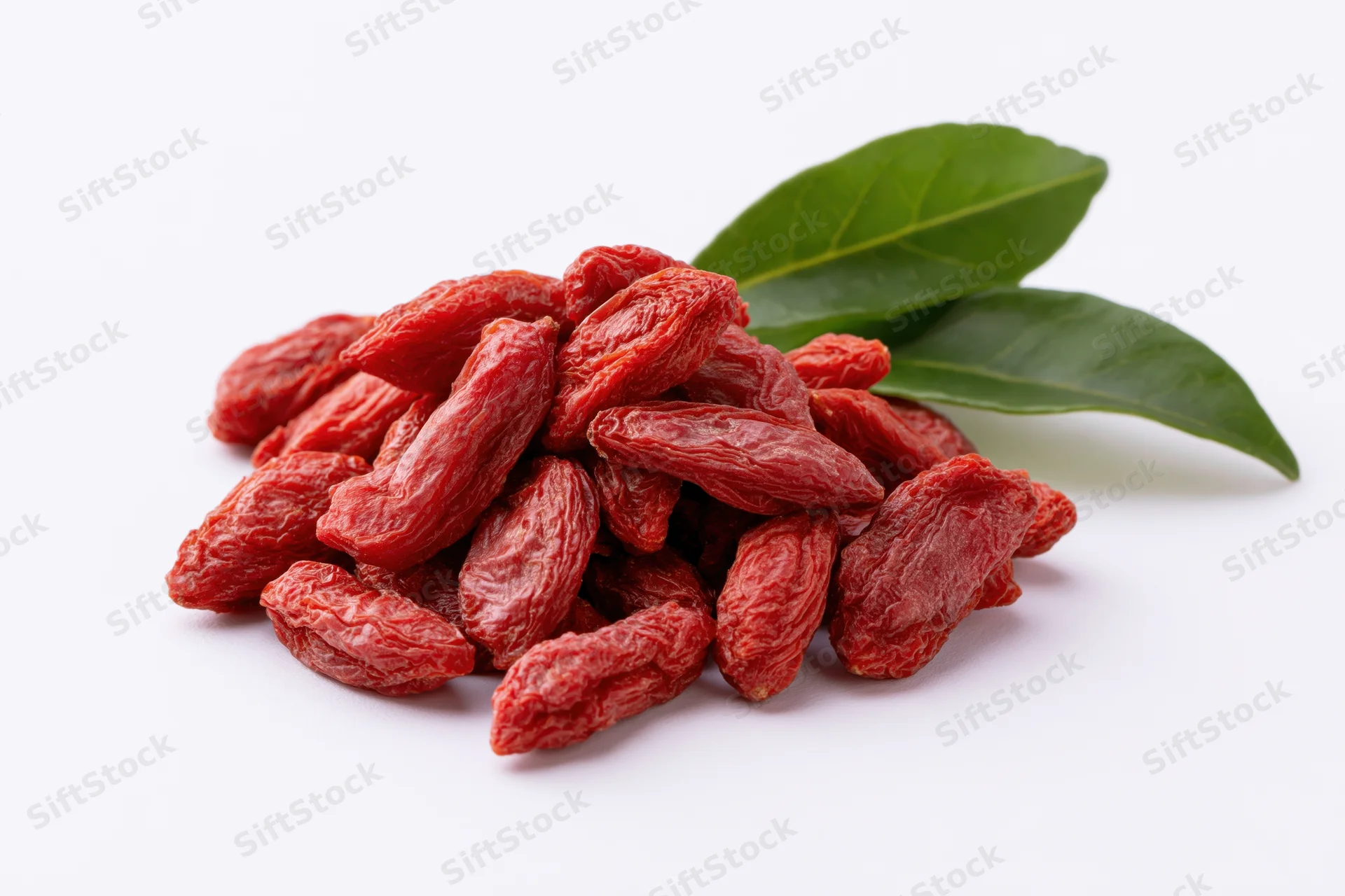 Pile of dried goji berries with two green leaves on white background