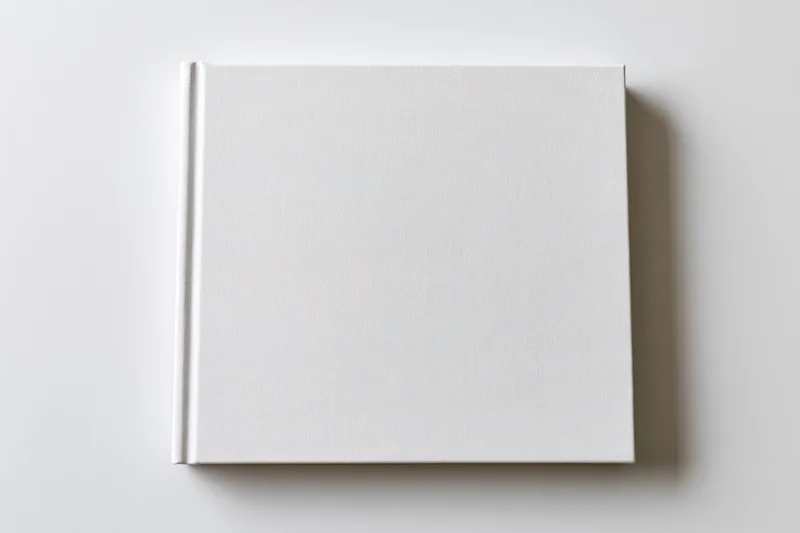 Square blank white hardcover book lying flat on a white surface