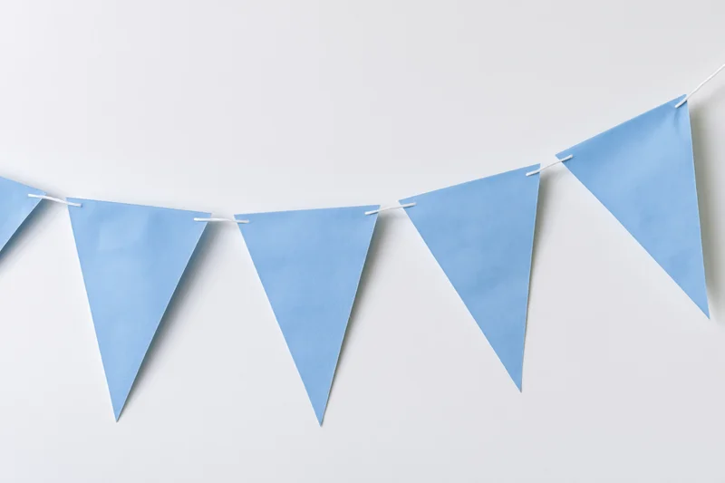 Light blue triangular paper bunting flags strung across a white wall