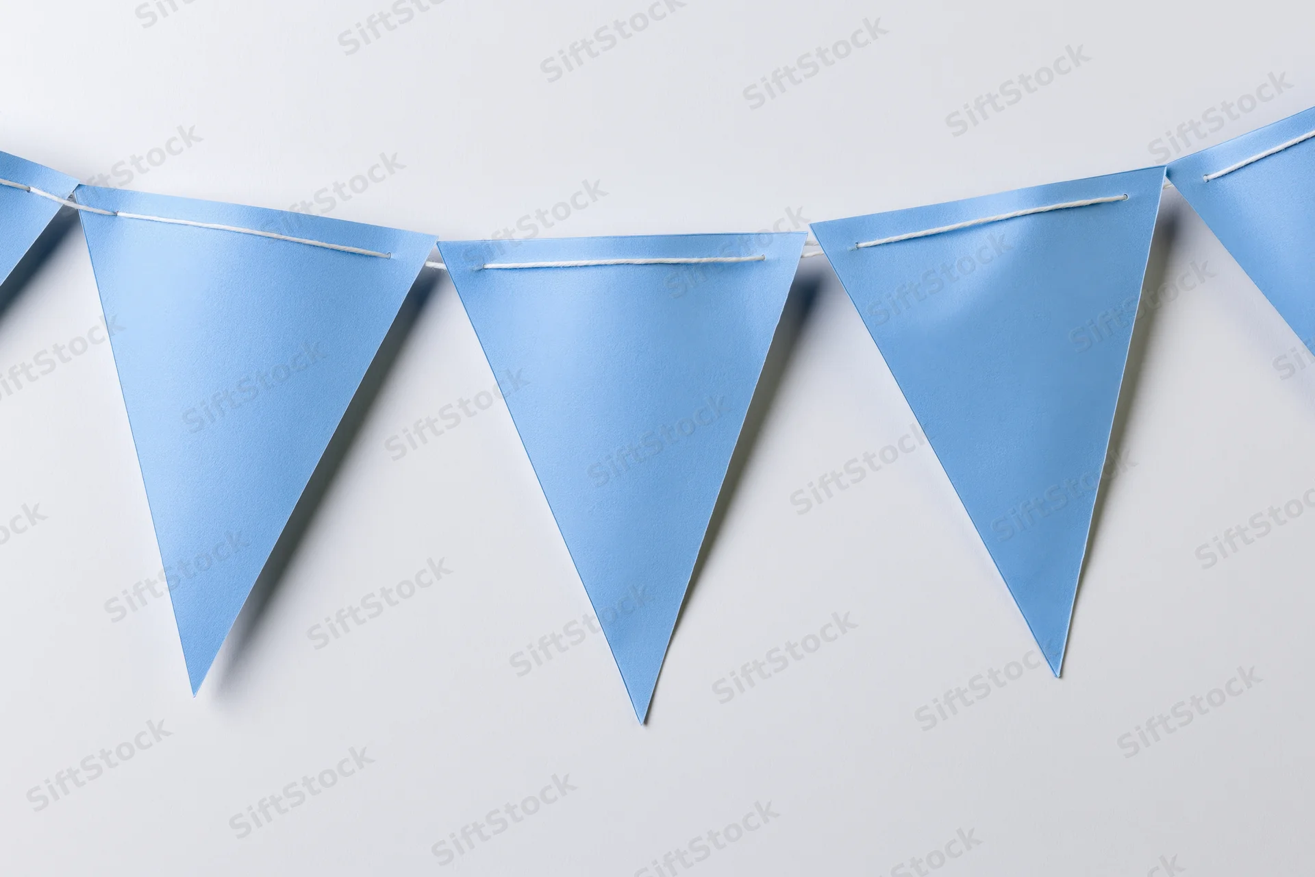 Light blue triangular paper bunting flags strung across a white wall