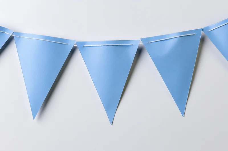 Light blue triangular paper bunting flags strung across a white wall