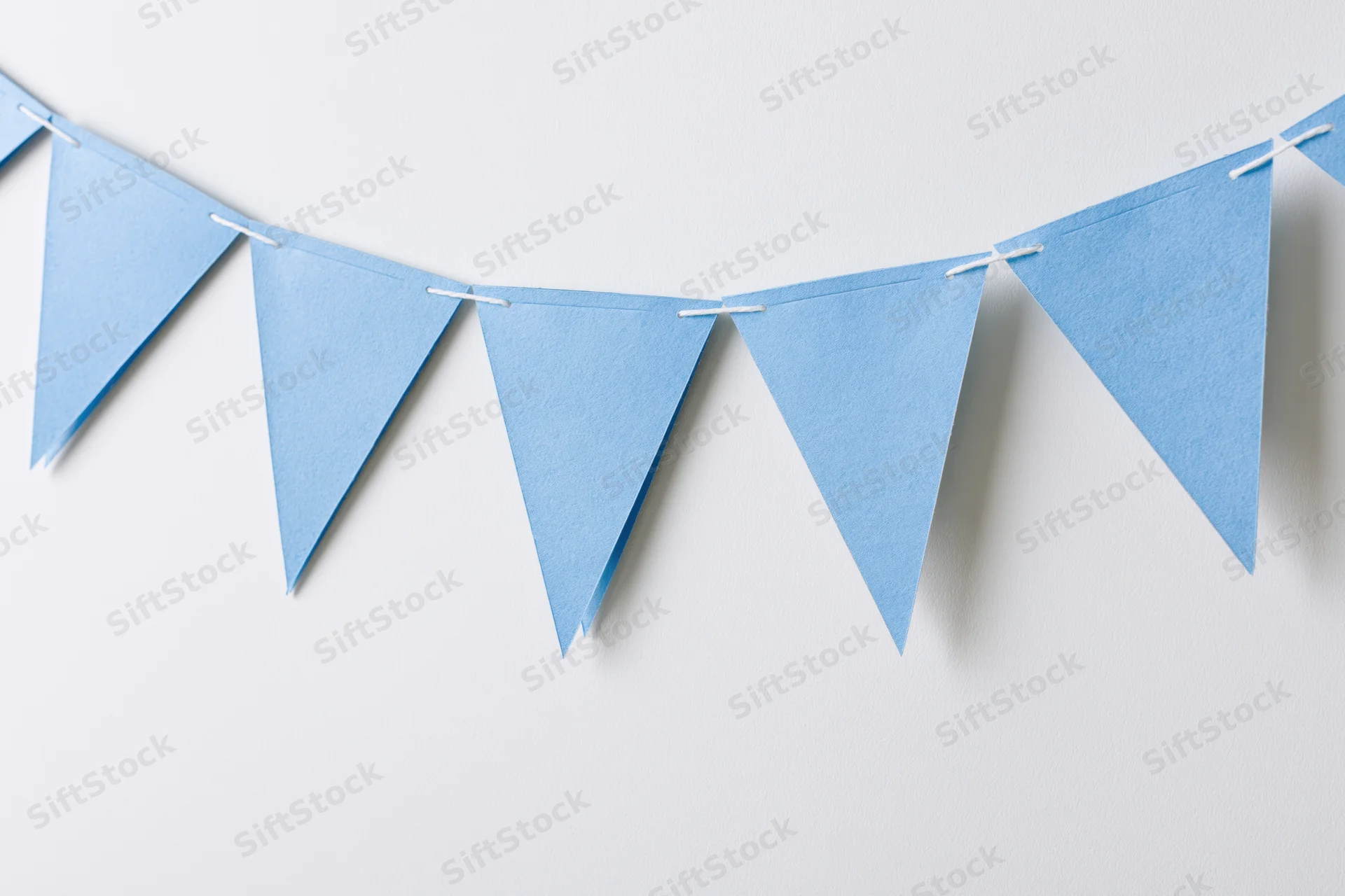 Light blue triangular paper bunting flags strung across a white wall