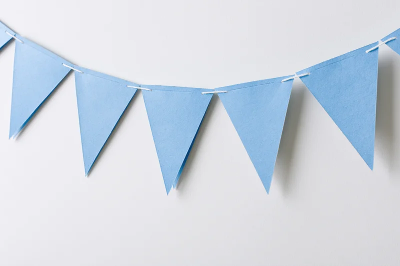Light blue triangular paper bunting flags strung across a white wall
