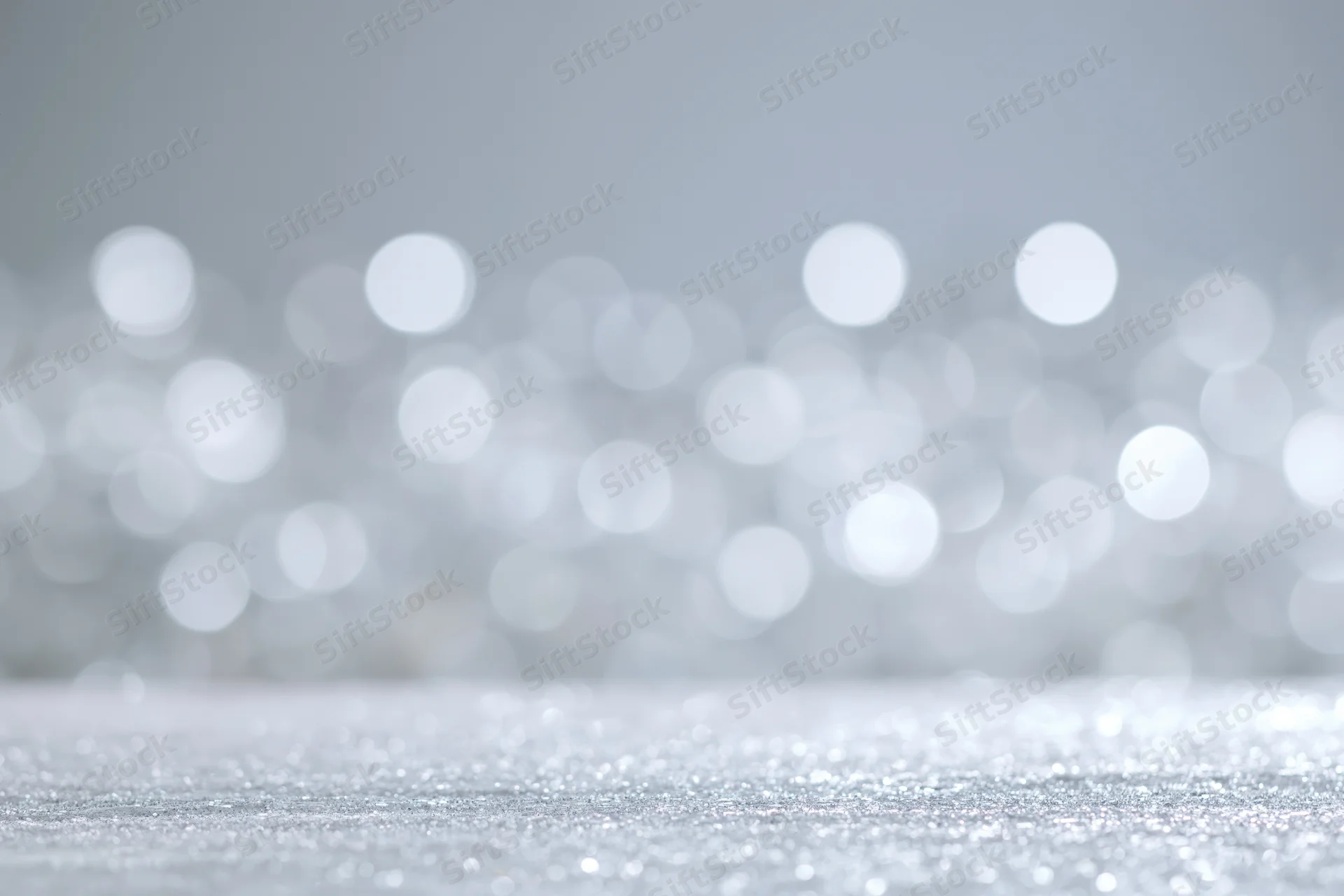 Silver glitter surface with blurred bokeh lights in background
