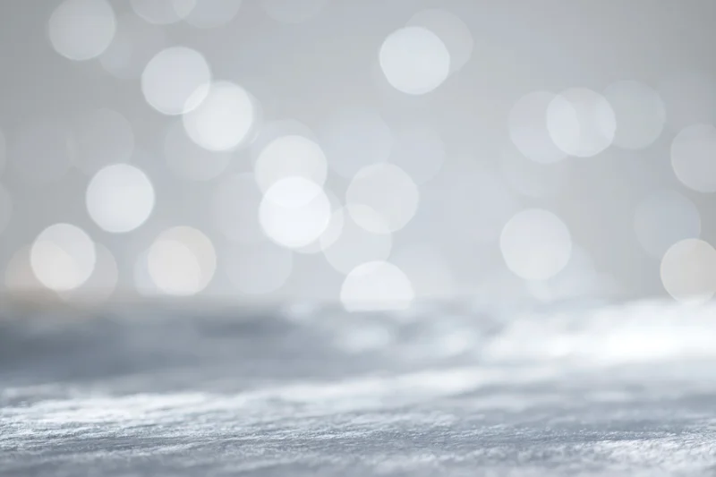 Abstract white and silver bokeh lights over a blurred reflective surface