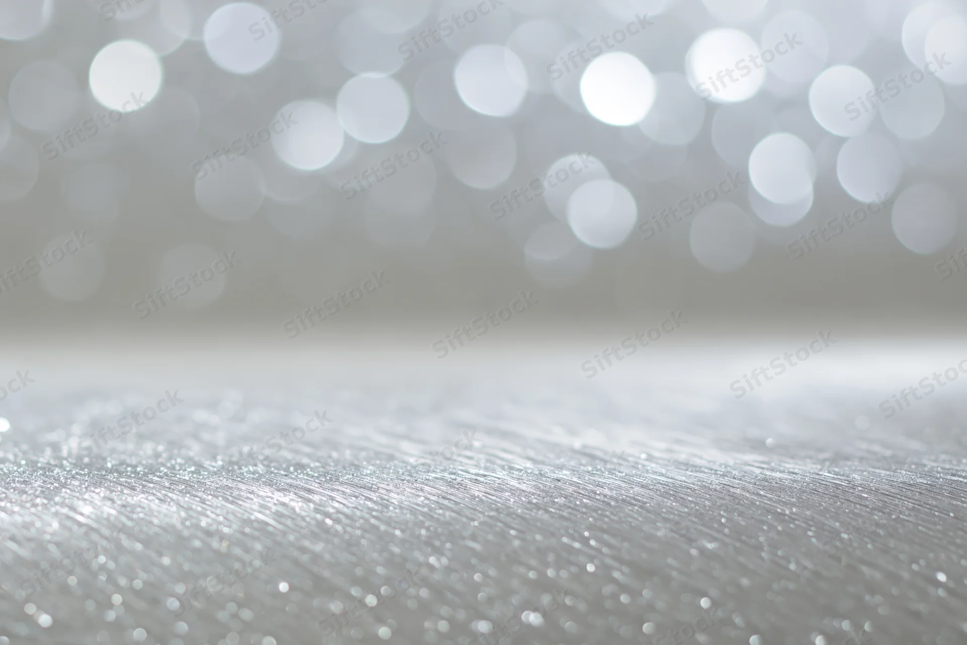 Silver glitter surface with bokeh lights in background