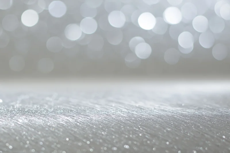 Silver glitter surface with bokeh lights in background