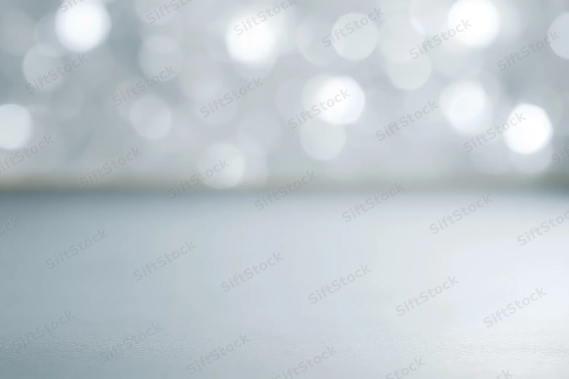 Soft white bokeh lights over a smooth surface as a festive background