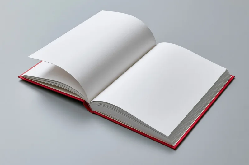 Open hardcover book with blank white pages lying flat on gray surface