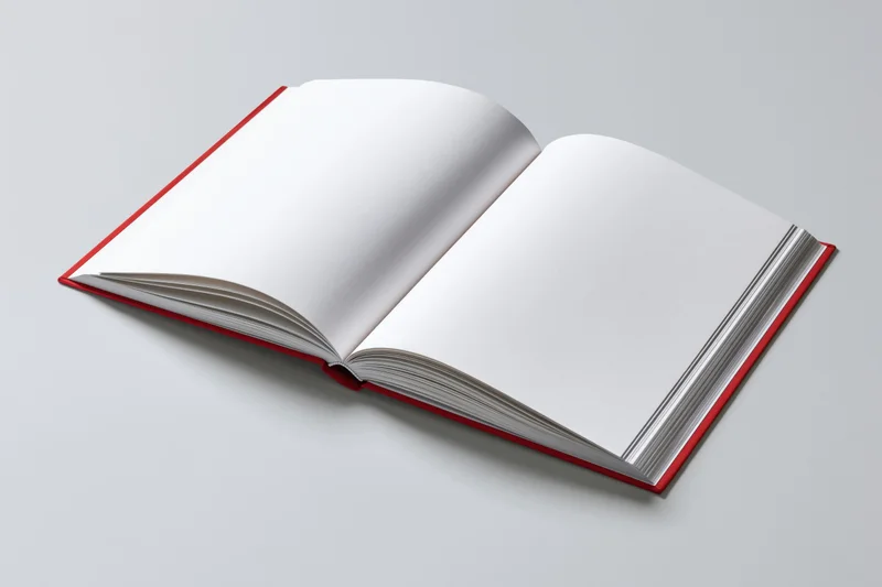 Open hardcover book with blank white pages and red cover lying flat on light surface