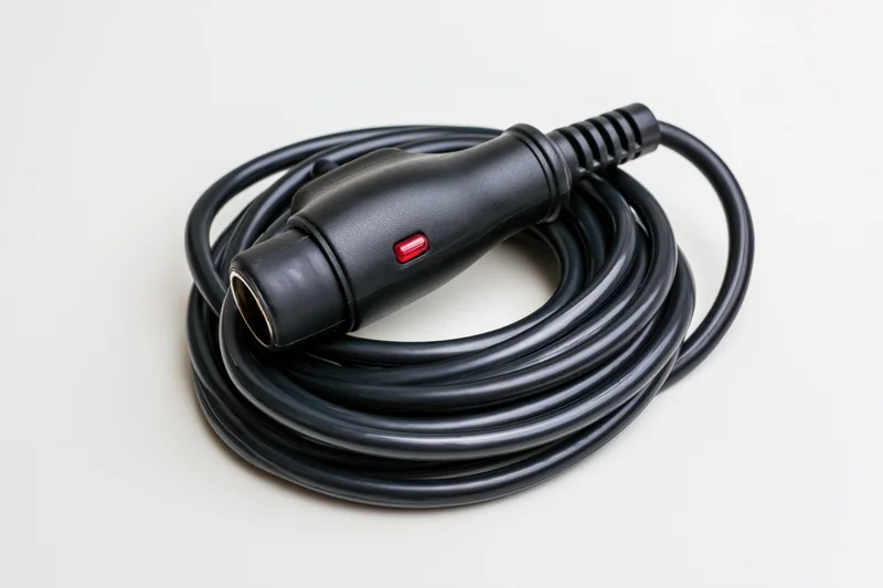 Coiled black car cigarette lighter adapter plug on white background