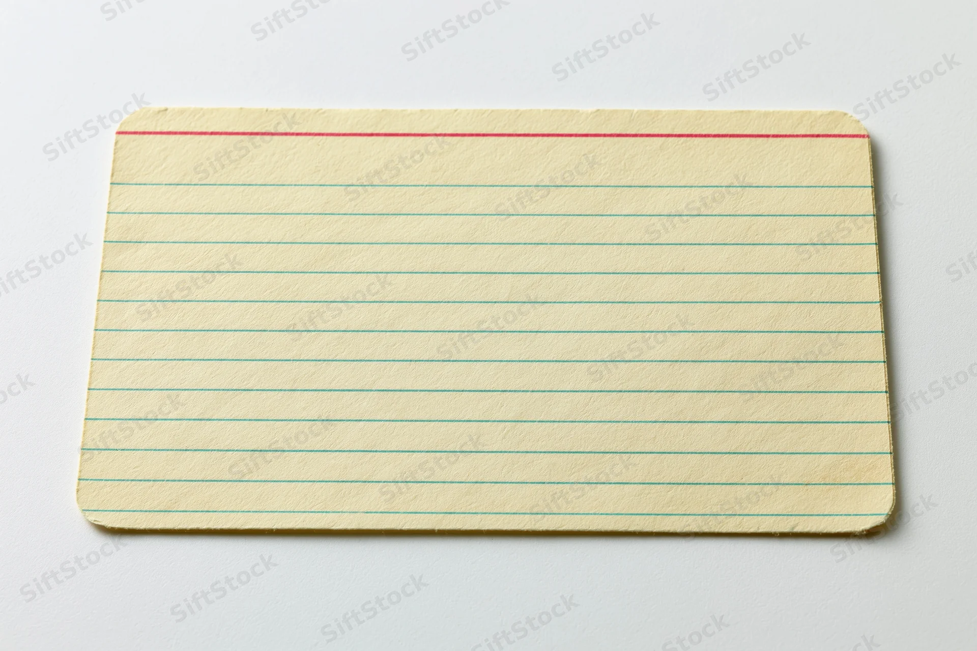 Vintage blank index card with green lines and red top line lying flat on white surface