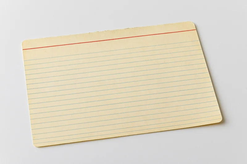 Vintage blank index card with blue lines and red margin line lying flat on white surface