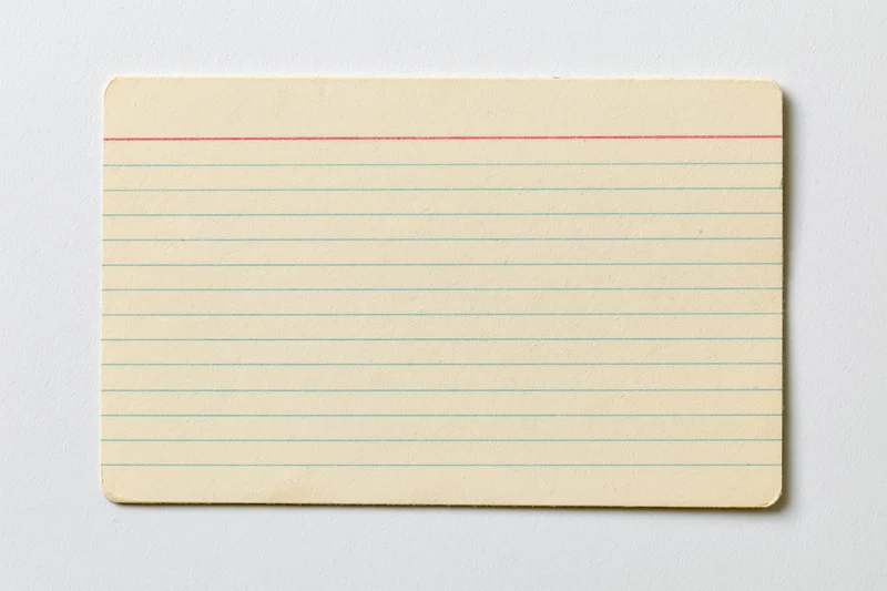 Vintage blank index card with red and blue lines lying flat on white surface