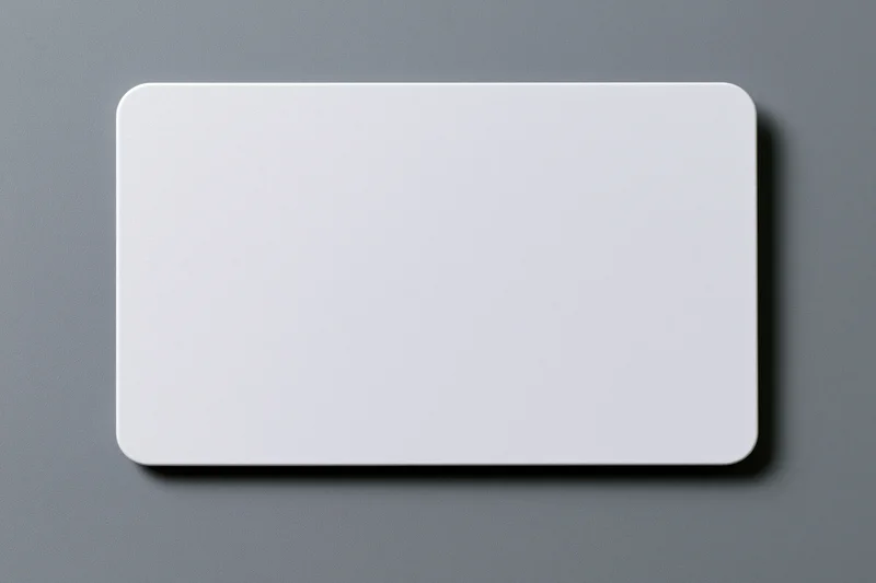 Blank white plastic card with rounded corners lying flat on gray surface