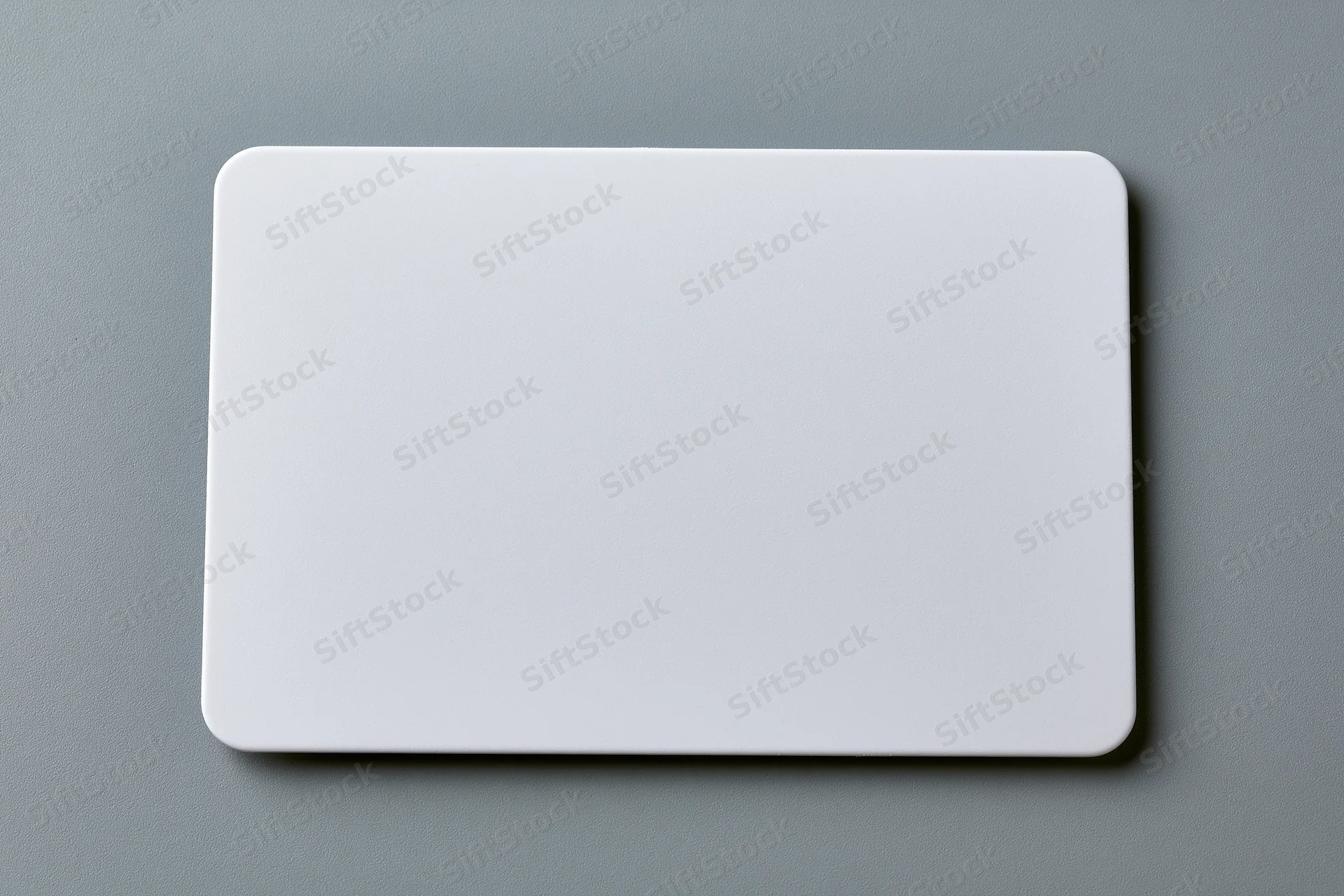 Blank white plastic card with rounded corners lying flat on gray surface