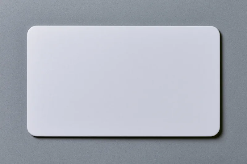 Blank white plastic card with rounded corners lying flat on gray surface