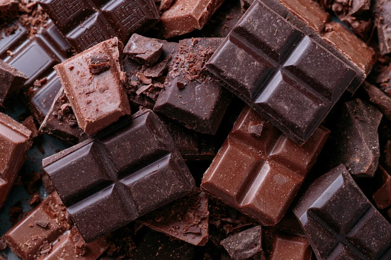 Broken dark chocolate pieces piled together in a closeup view