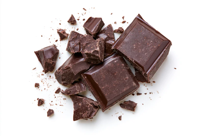 Broken dark chocolate bar pieces scattered on a white background
