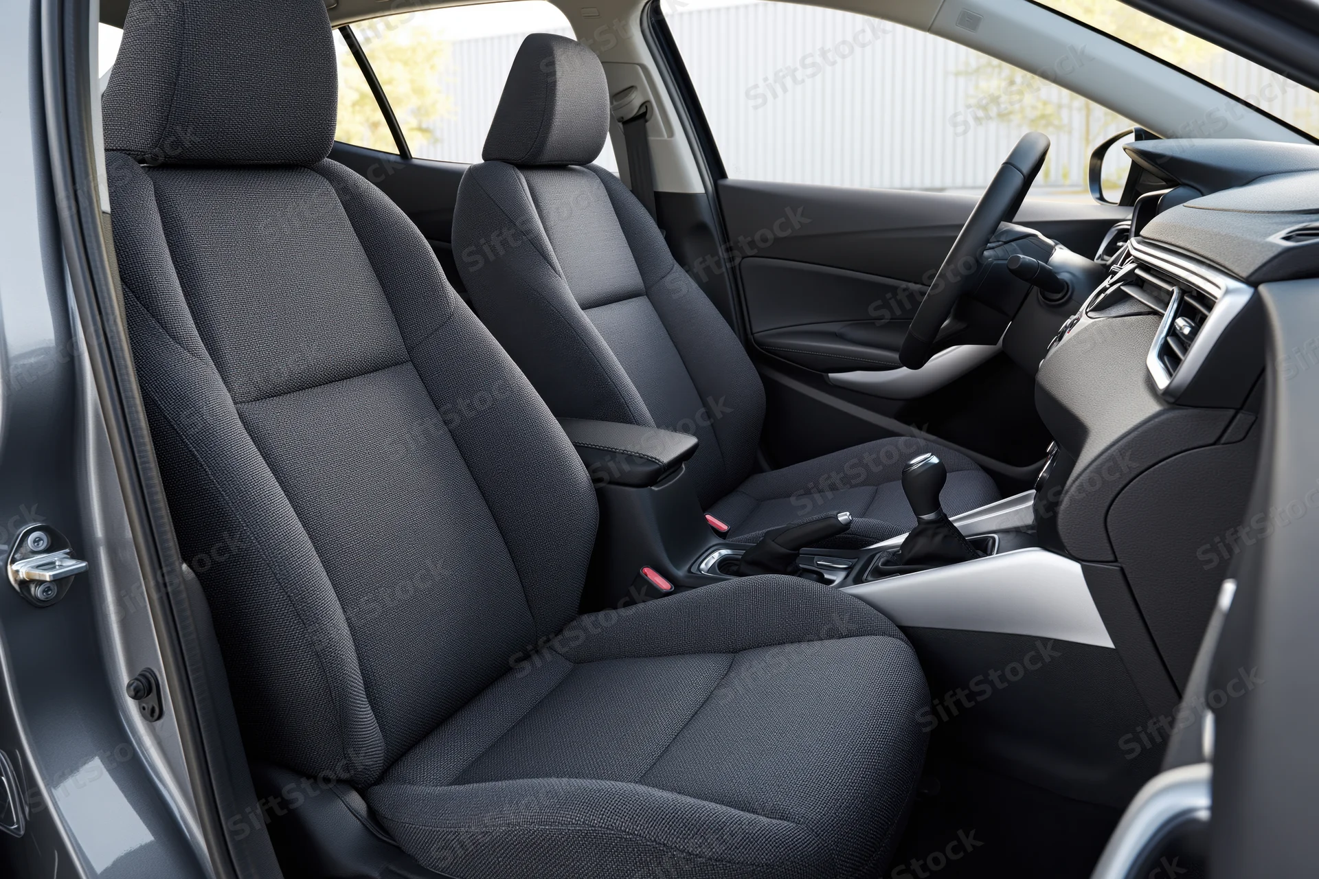 Front seats and dashboard of a car interior viewed from open passenger door