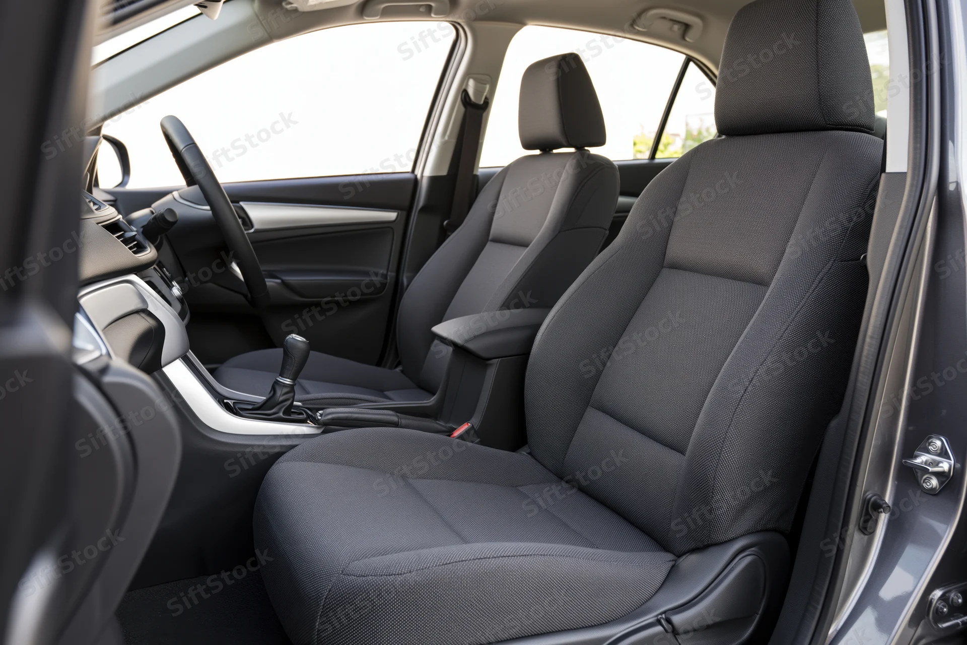 Front seats and dashboard of a car interior viewed from open passenger door
