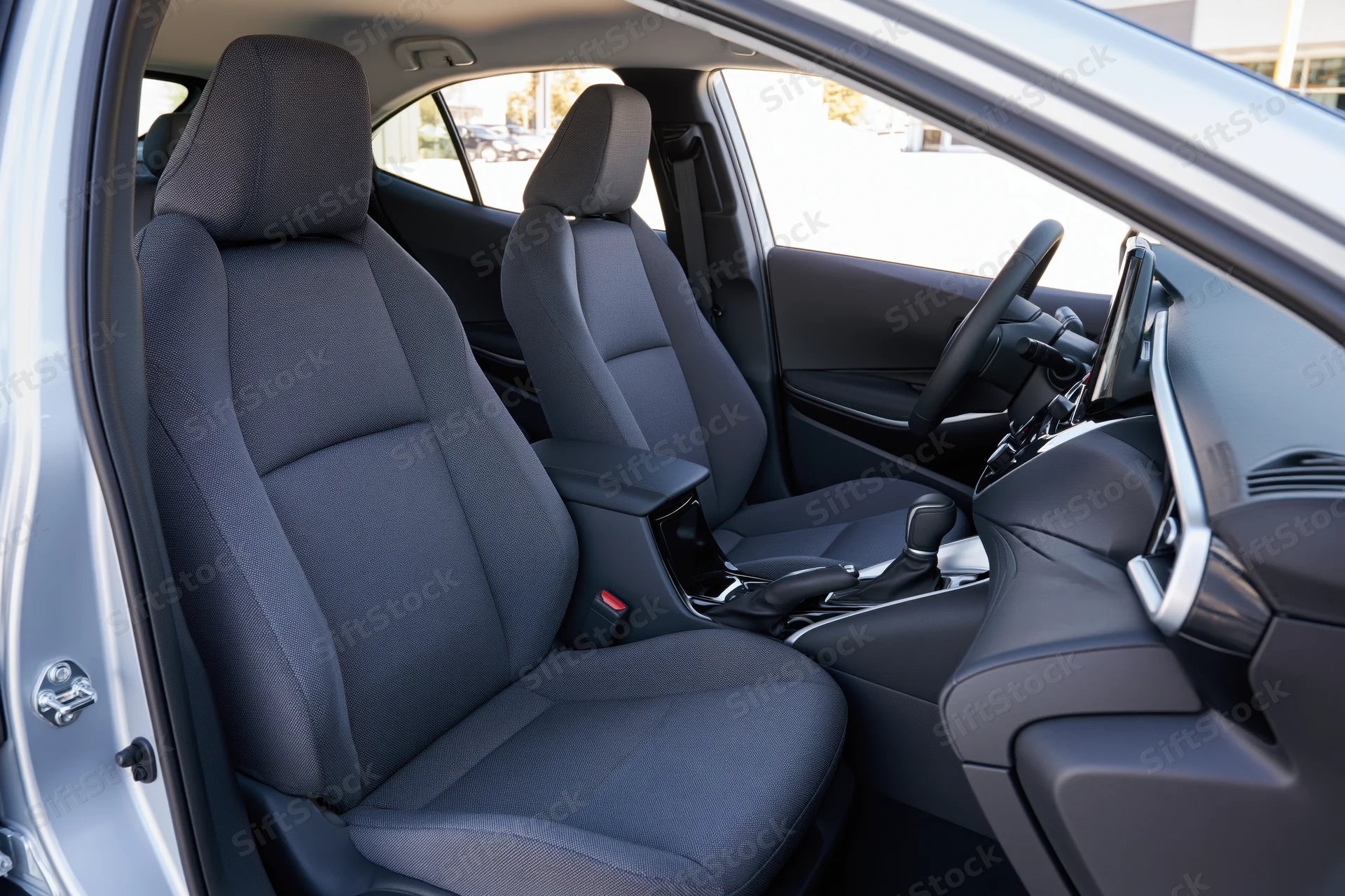 Front seats and dashboard of a car interior viewed from open passenger door
