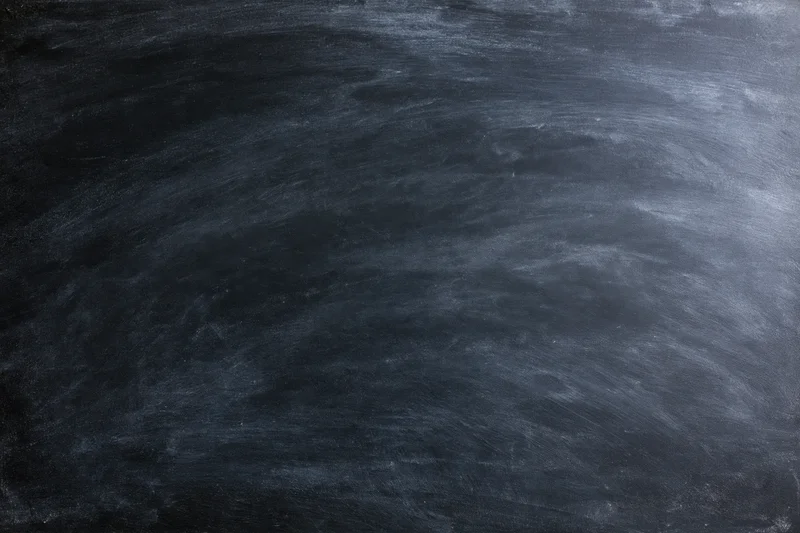 Close-up of a blank black chalkboard surface with smudged white chalk marks filling the frame
