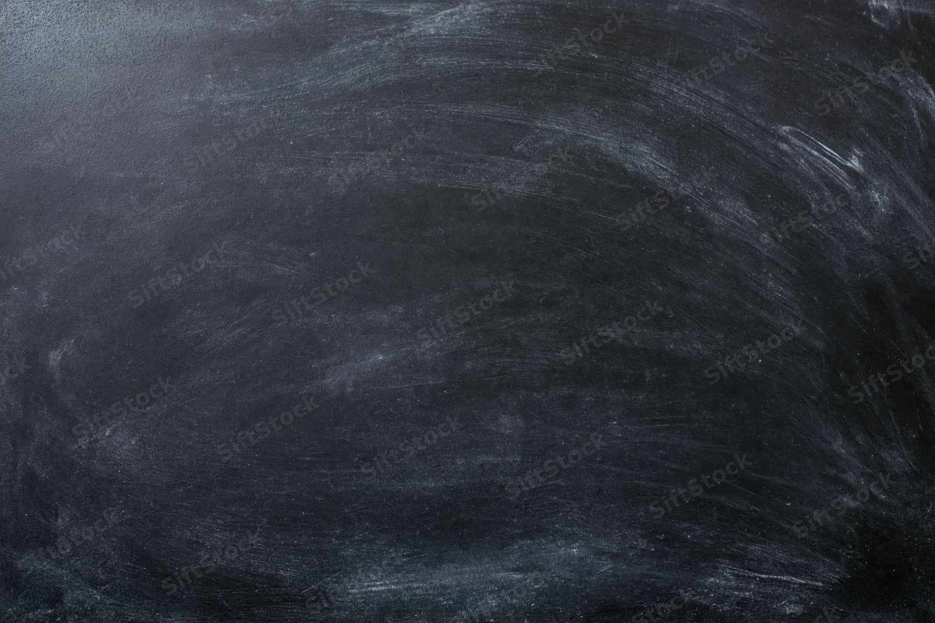 Close-up of a blank black chalkboard surface with smudged white chalk marks and erased residue, filling the frame