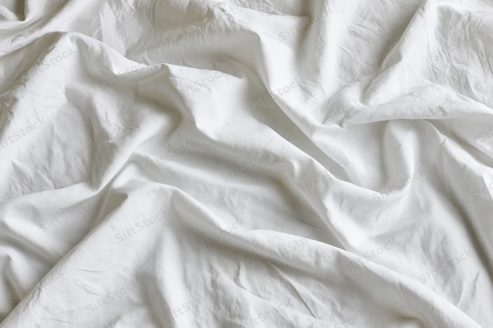 Crumpled white cotton bed sheet in close-up flat lay view