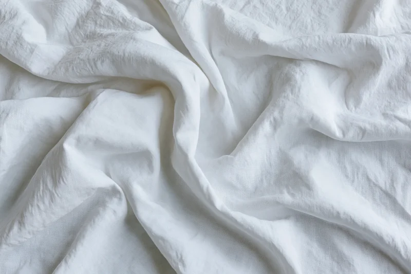 Crumpled white cotton bed sheet in close-up flat lay view