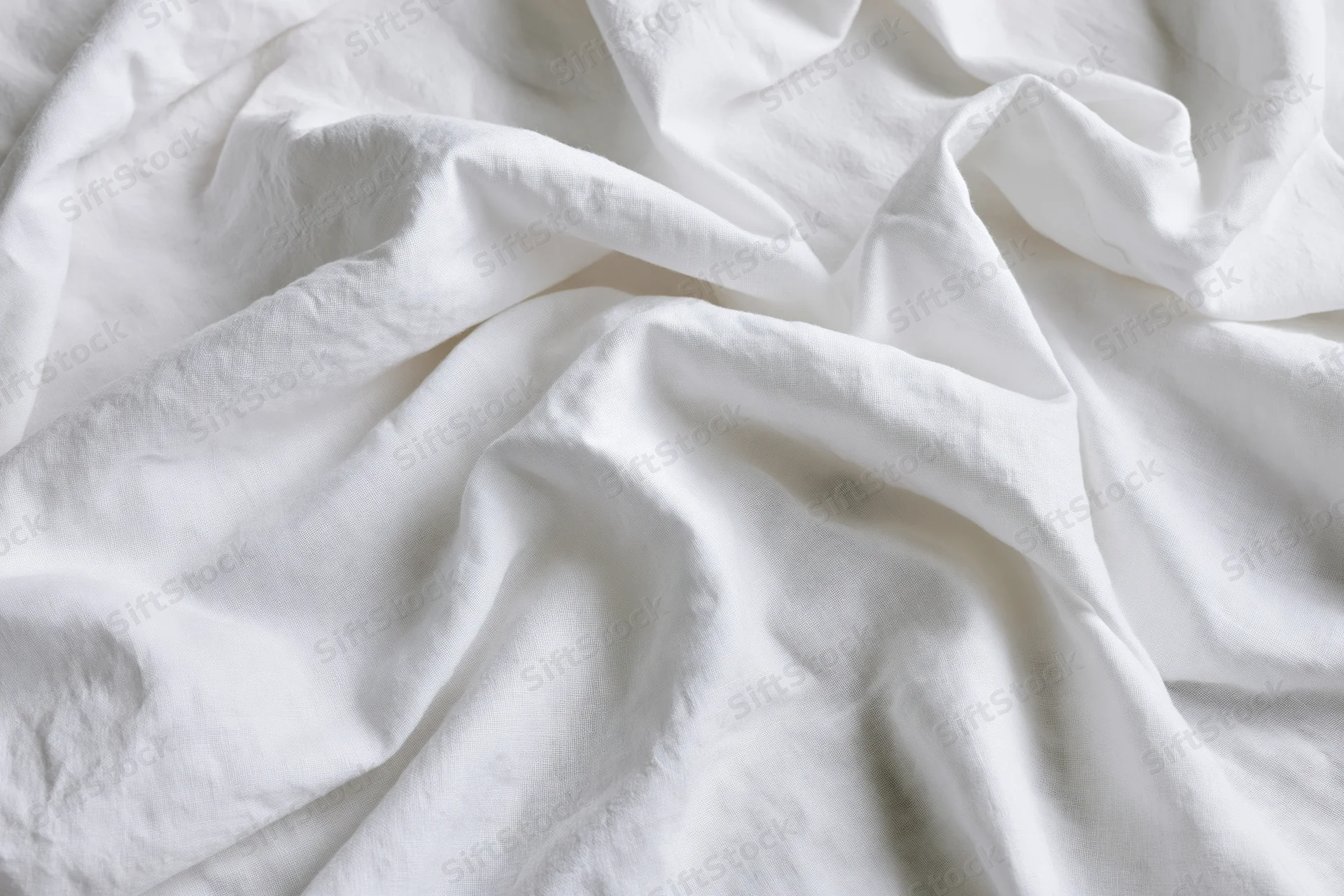 Crumpled white cotton bedsheet in close-up flat lay view