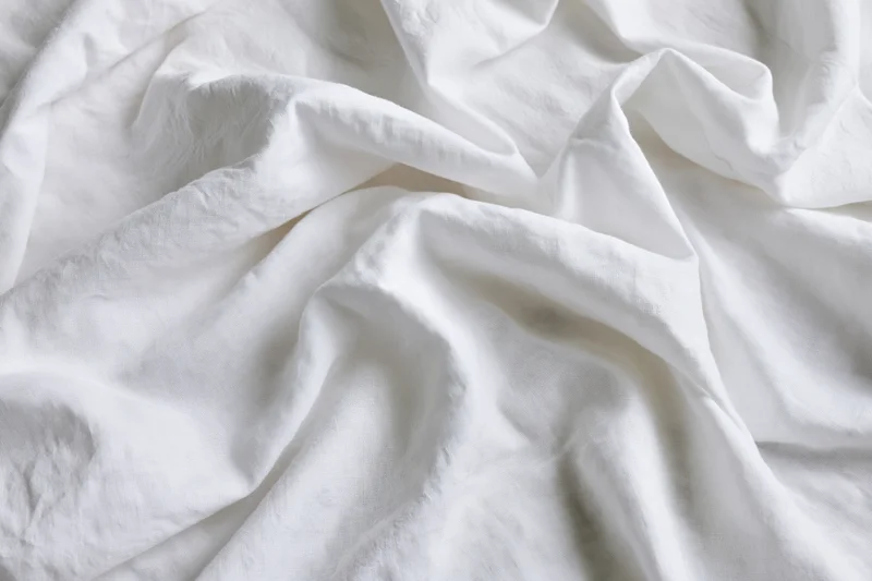 Crumpled white cotton bedsheet in close-up flat lay view