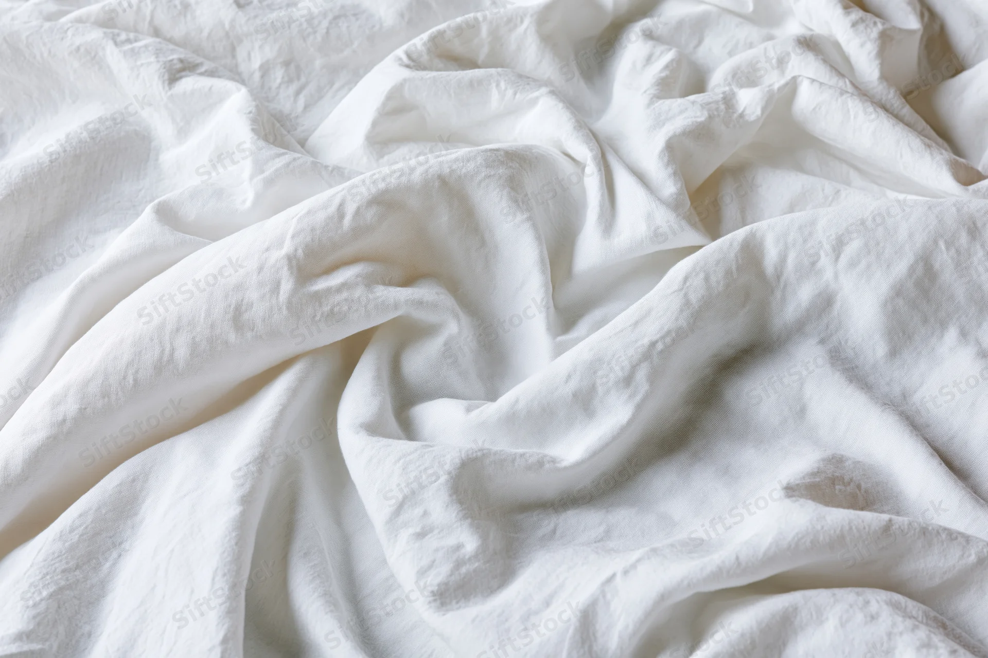 Crumpled white cotton bed sheet in close-up flat lay view