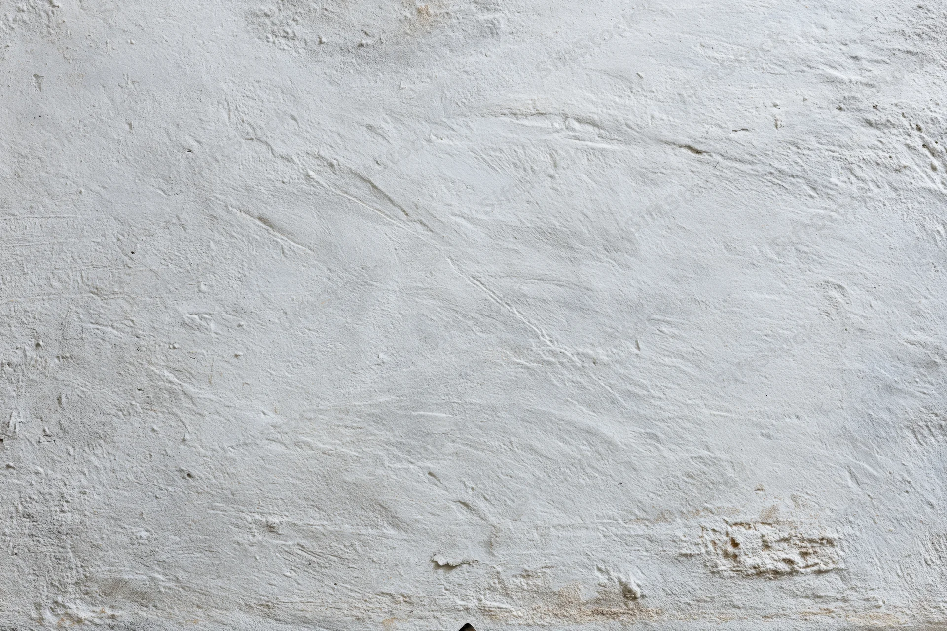 Close-up of a weathered white concrete wall surface with cracks and stains