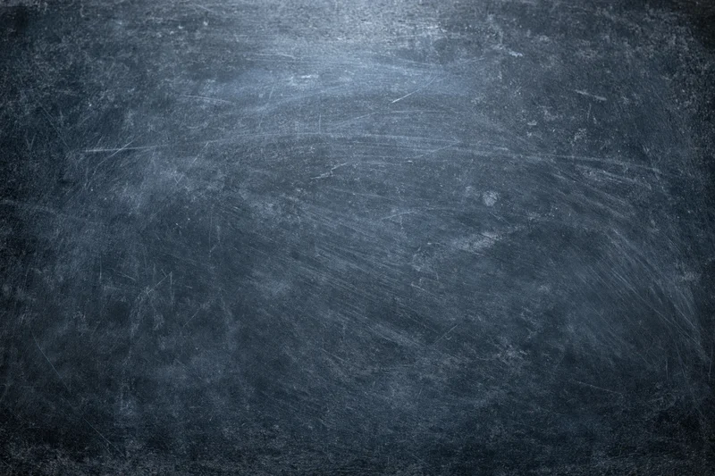Close-up of a weathered dark chalkboard surface with scratches and smudges