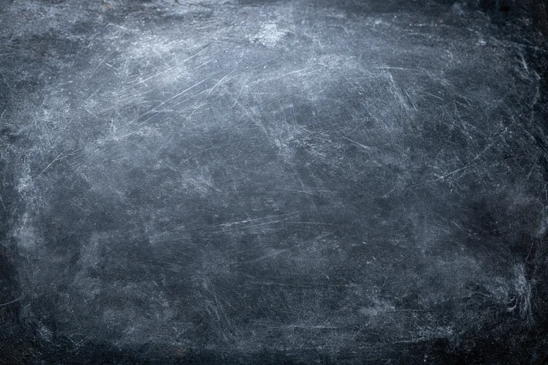 Close-up of a weathered dark chalkboard surface with scratches and smudges