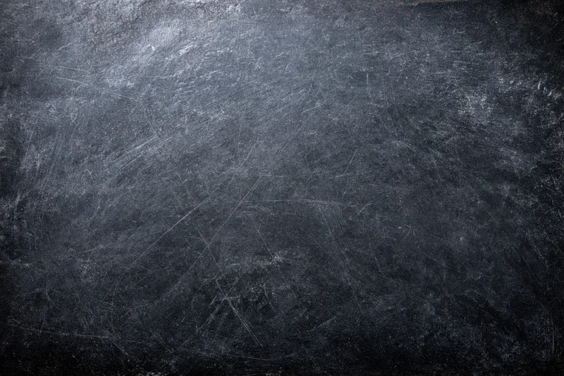Close-up of a weathered dark chalkboard surface with scratches and smudges