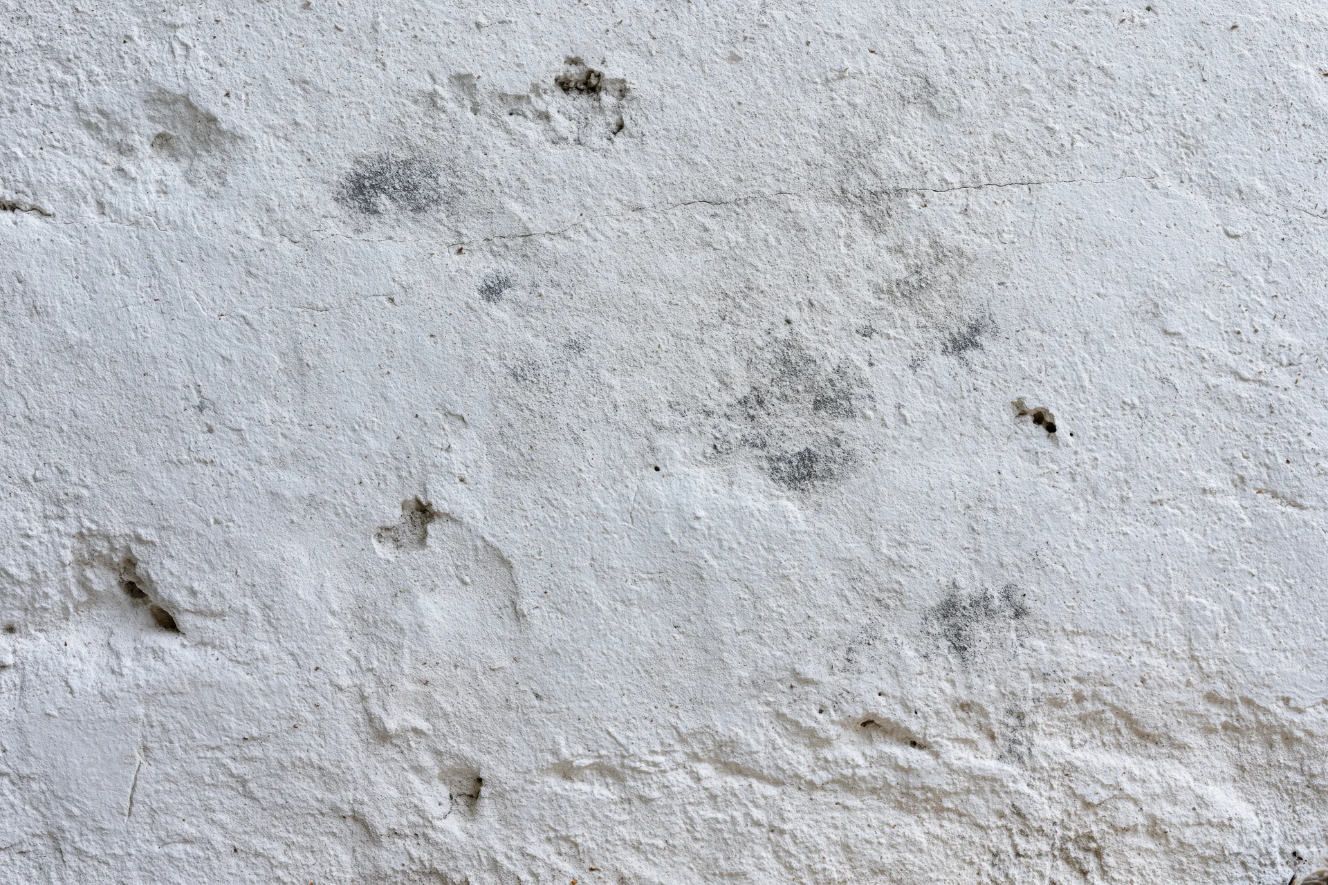 Close-up of a weathered concrete wall surface with cracks and stains