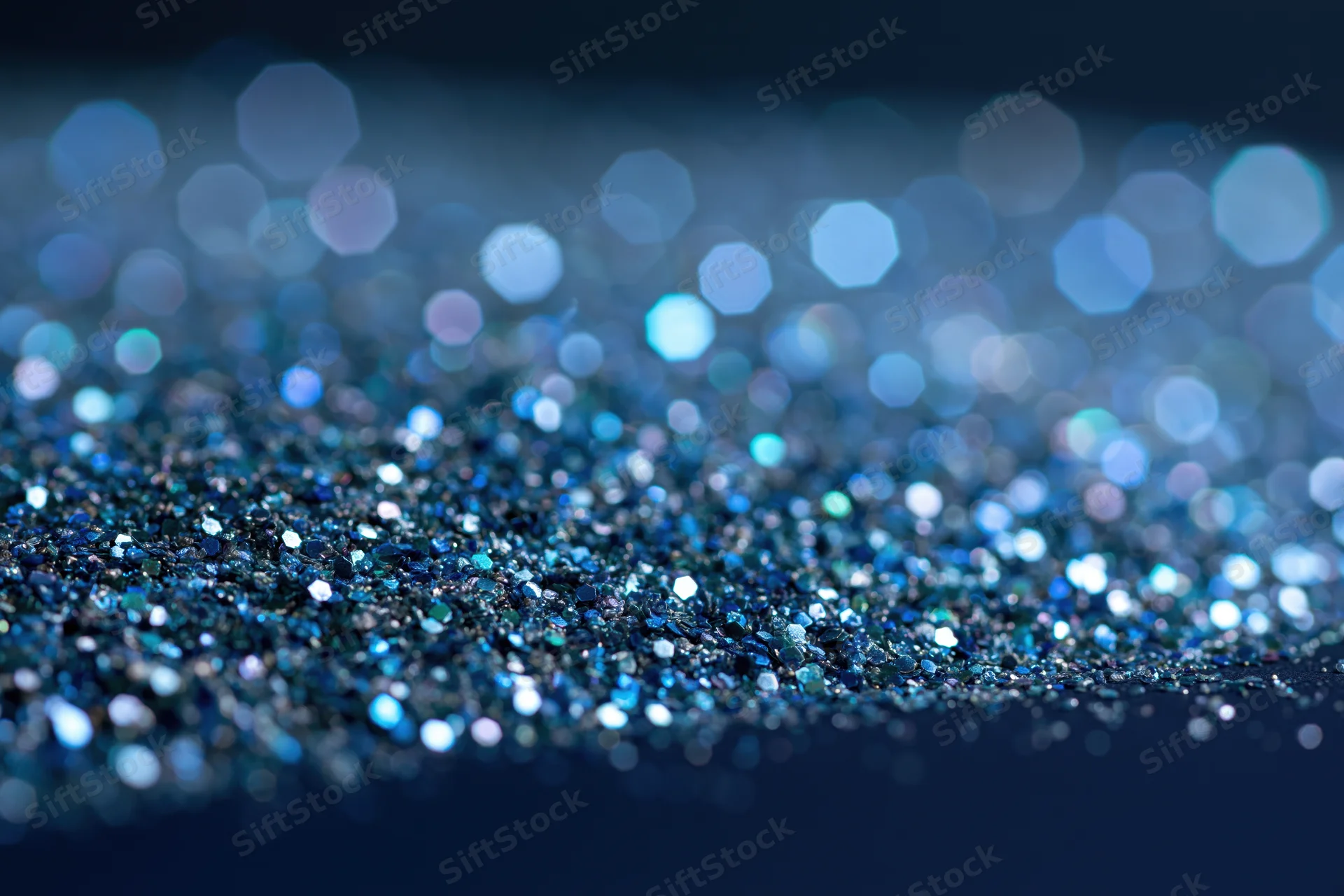 Close-up of blue glitter surface with scattered light reflections and bokeh effect