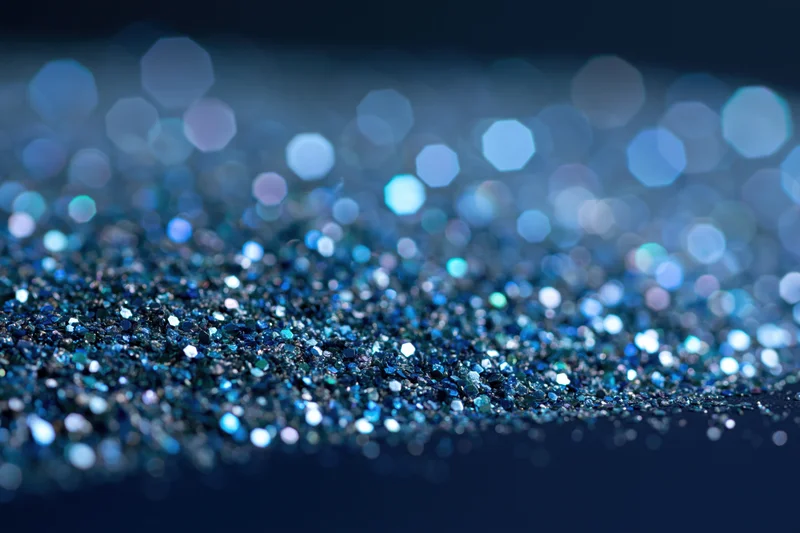 Close-up of blue glitter surface with scattered light reflections and bokeh effect