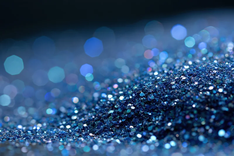 Close-up of blue glitter surface with scattered light reflections and bokeh effect